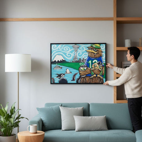 A man is hanging a colorful painting on a wall in a living room.