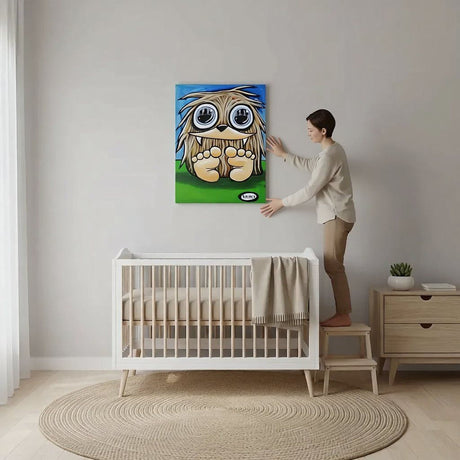 A woman is standing on a step ladder, placing a large, colorful painting of a cartoon character on the wall of a nursery room.